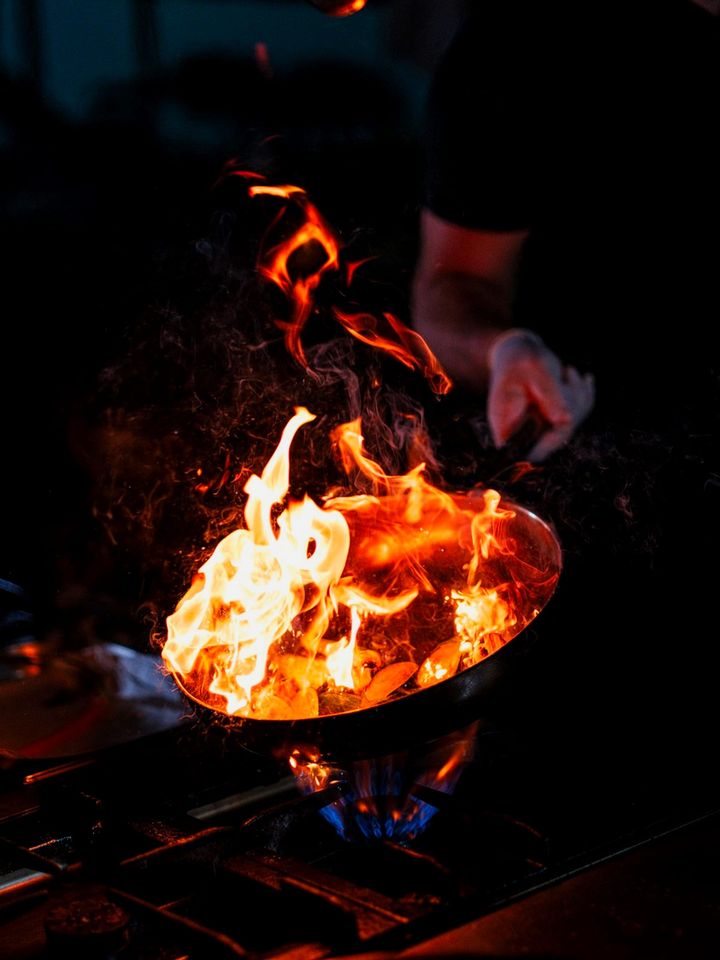 Suasana dapur Ruang Rempah saat memasak, uap dan api terlihat